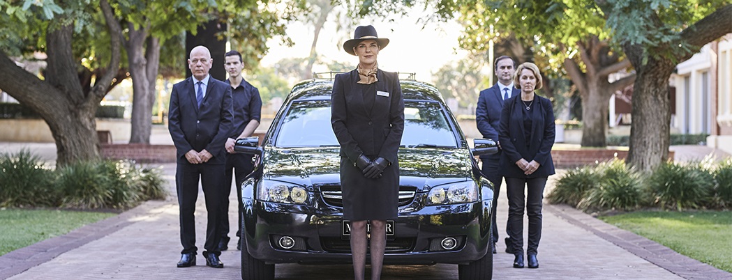 Perth Funeral Services - Funeral director and pallbearers standing by the black hearse for the funeral service at the MCB Karrakatta to commence.